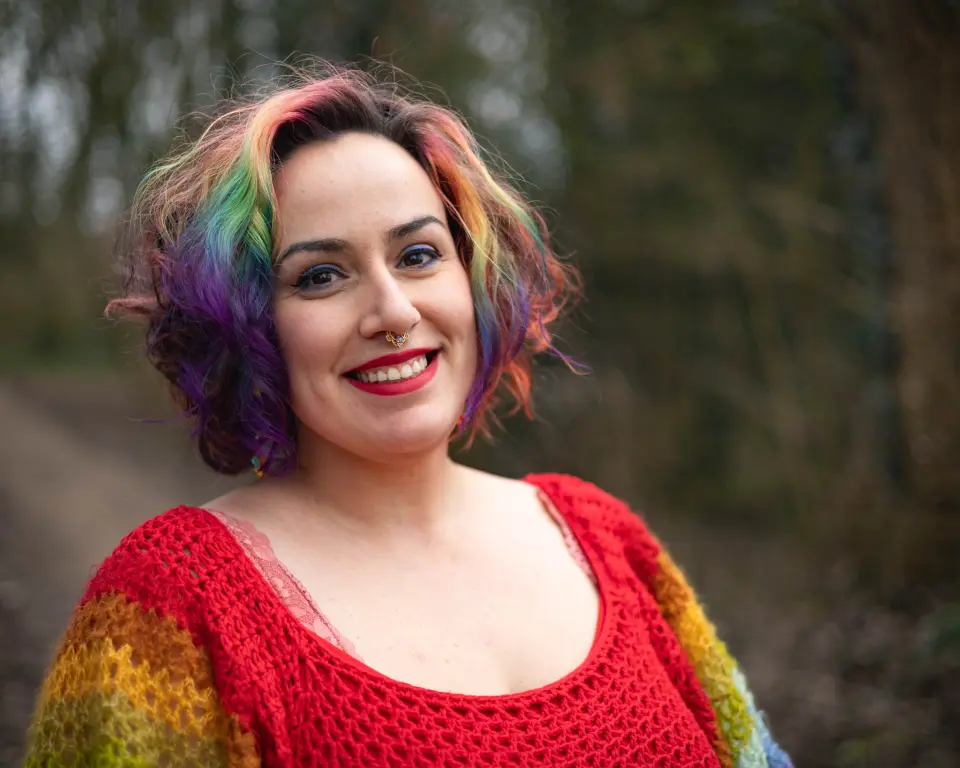 Jopie Louwe Kooijmans. Ze draagt een trui in verschillende kleuren en ook haar haar is in verschillende kleuren geverfd.