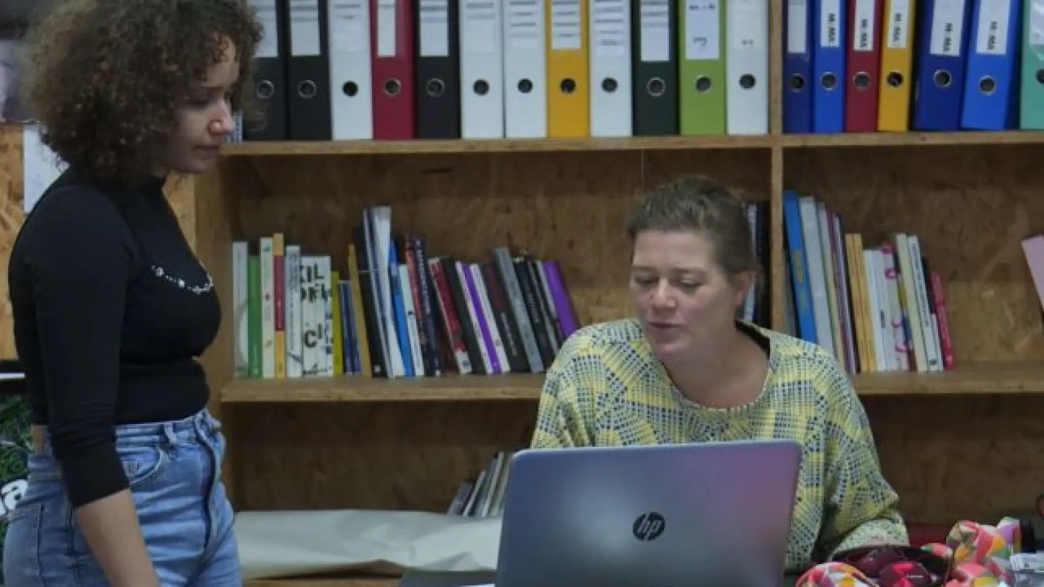 Twee collega's kijken in een kantoorruimte naar een laptop.