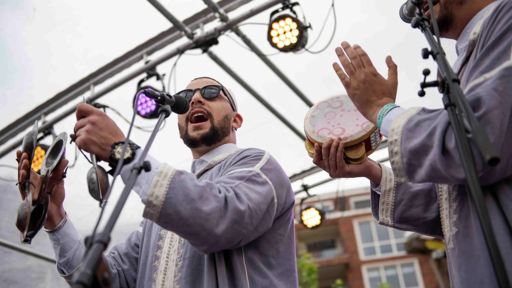 Twee mannen in traditionele kleding maken muziek op het podium. Ze zingen en begeleiding zichzelf met traditionele instrumenten.