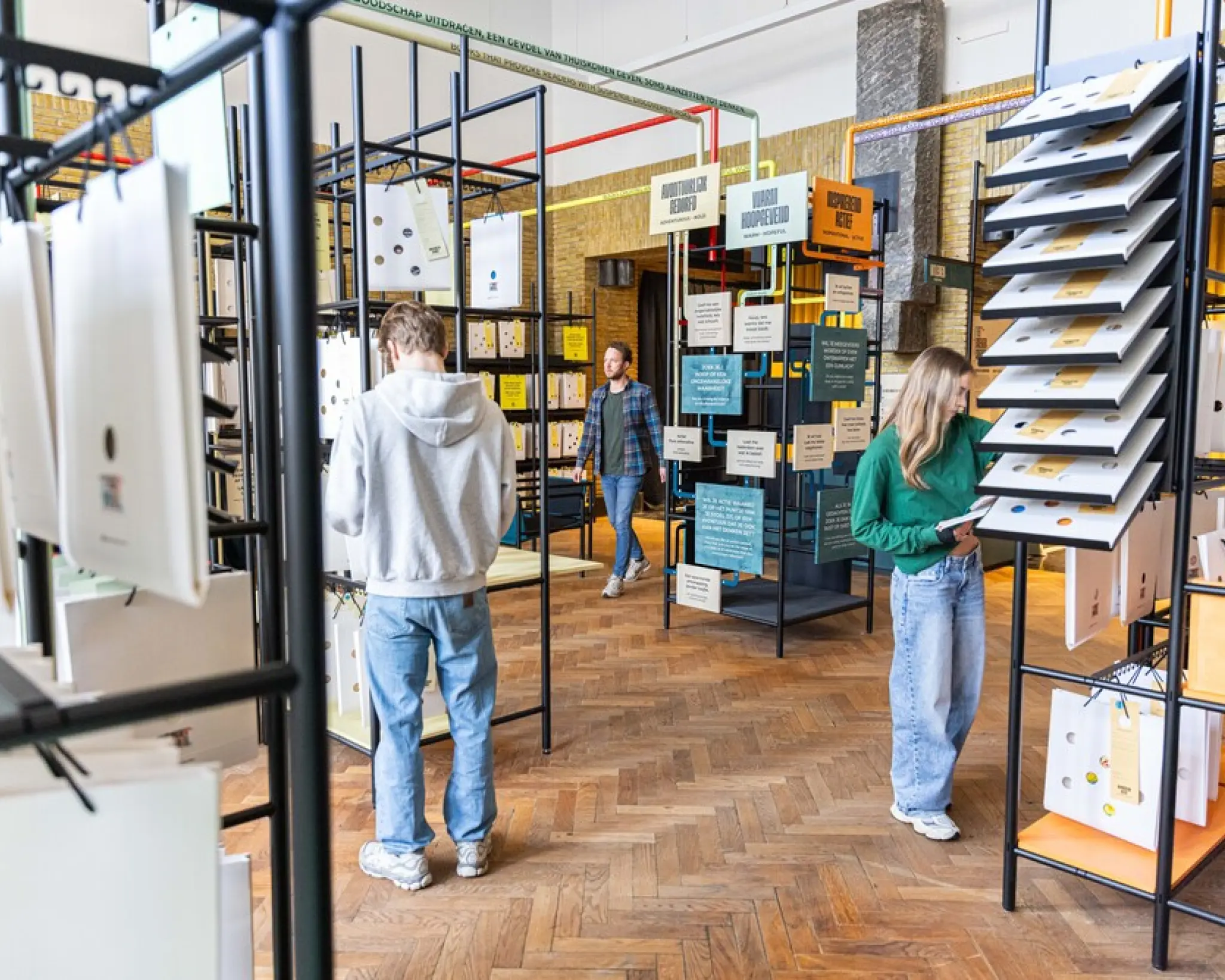 Bezoekers van de bibliotheken lopen tussen de rekken met tasjes en de beslisboom door. Sommigen houden een tasje in hun hand en bestuderen aandachtig de beschrijving